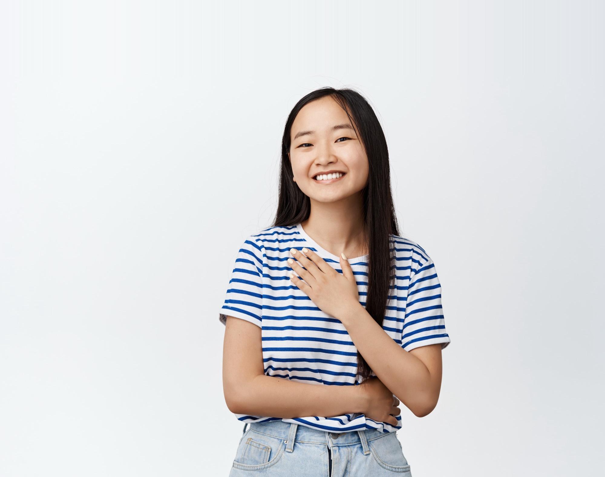 A young woman in a striped shirt, smiling with a hand on her chest